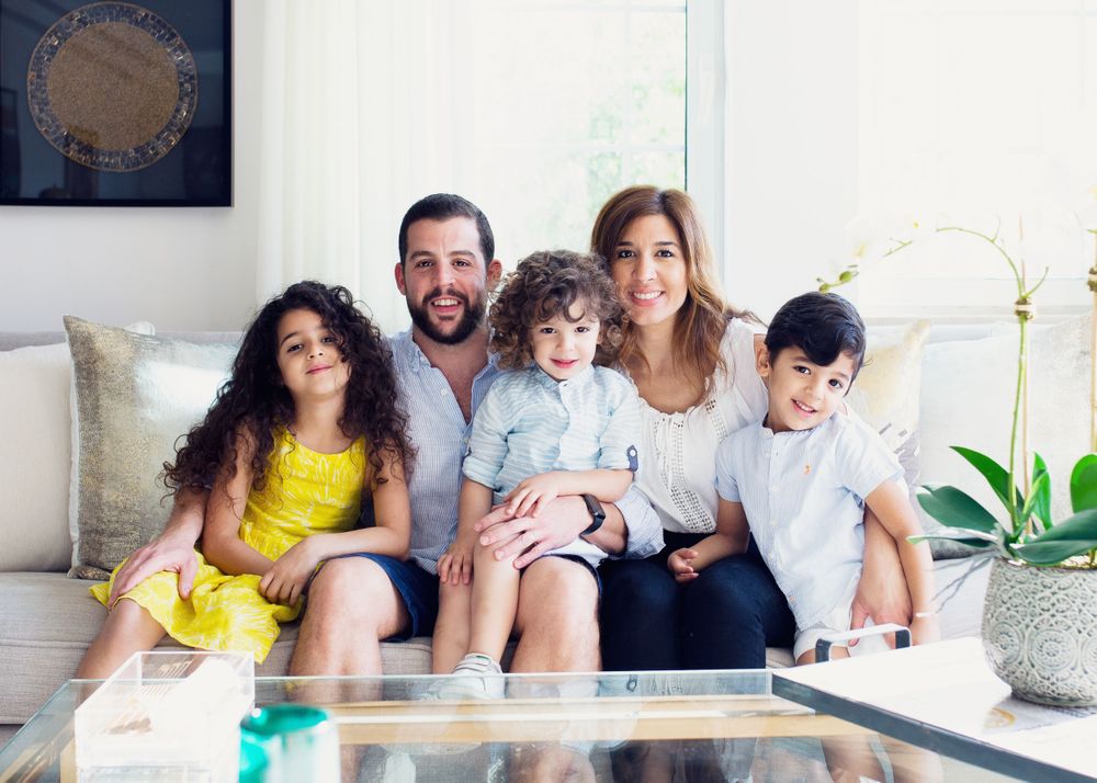 A family squeezing onto the couch for a in-home, lifestyle, family photo shoot.