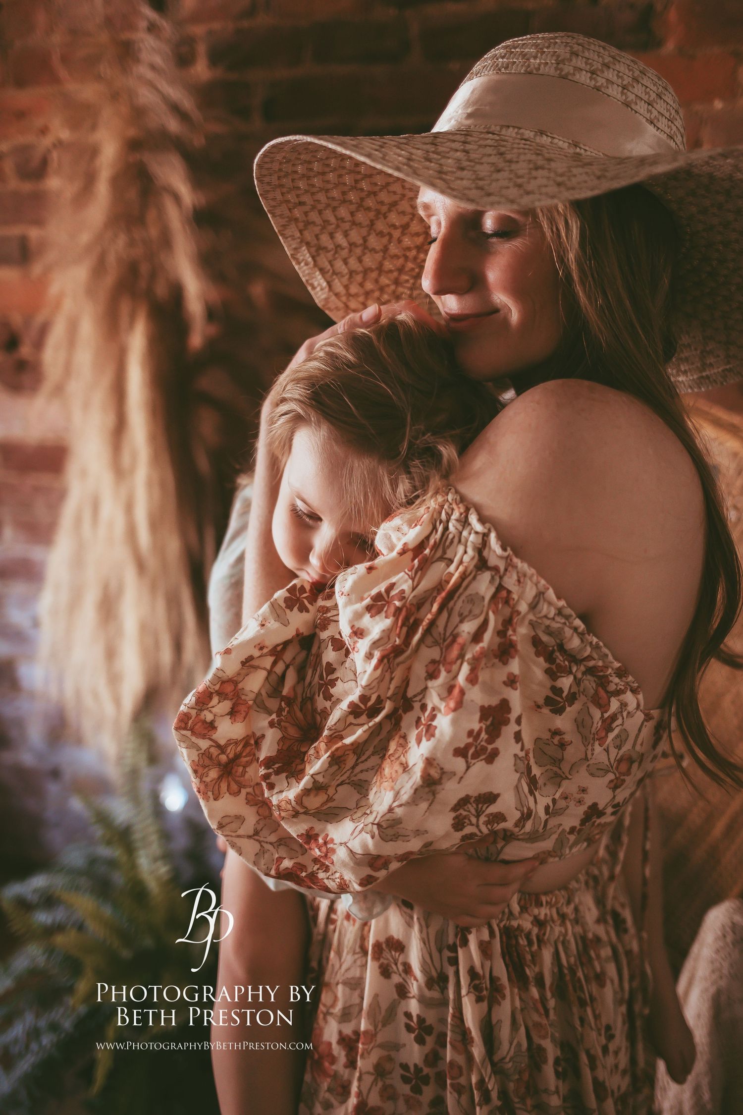 A dreamy portrait with a sunhat and floral dress against a rustic brick wall.