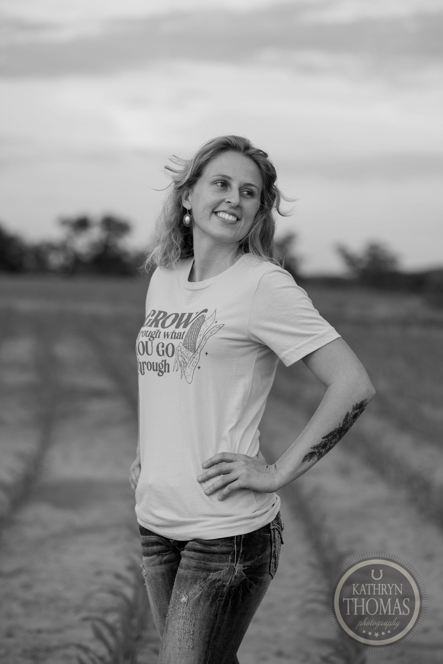 Black and white portrait showing casual farmhouse style against cloudy rural backdrop.