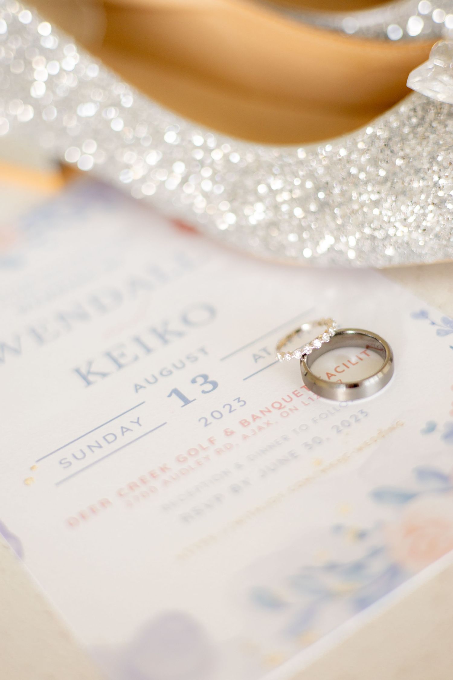 Wedding ring on invitation with glittery details showing date.