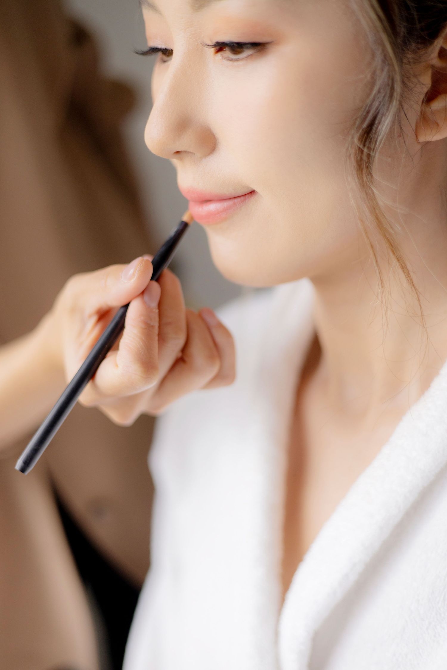 Close-up detail shot of delicate bridal makeup application with thin brush.