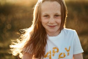 A person wearing a 'Happy' t-shirt smiles during a sunset photoshoot.