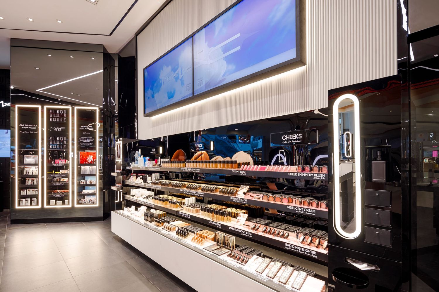 MAC cosmetics product display shelves with digital screens and modern lighting.