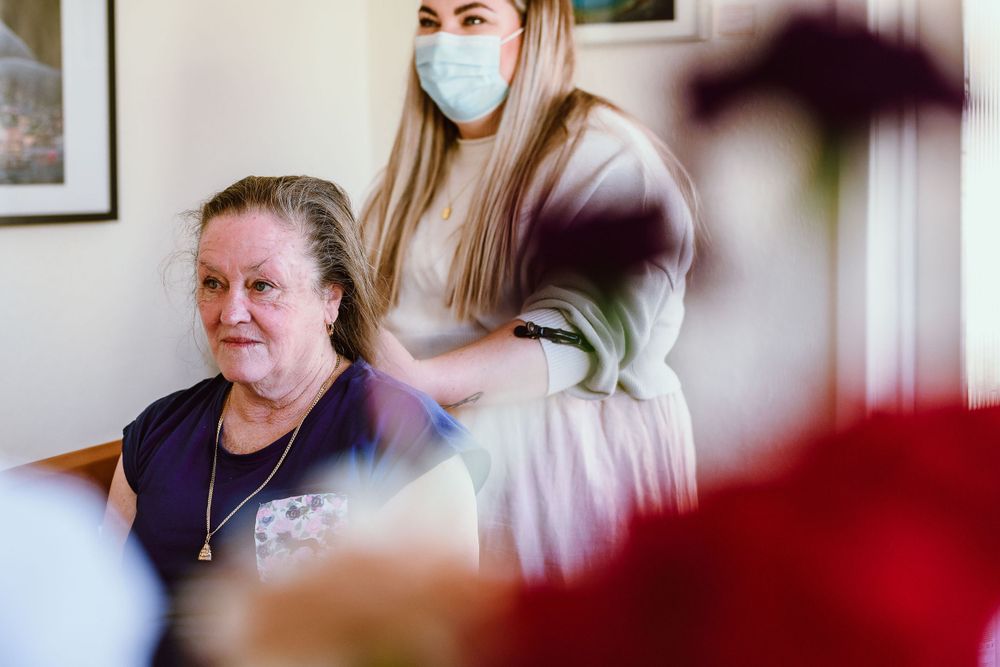A hair styling session in progress in a bright indoor setting with someone wearing a protective mask.