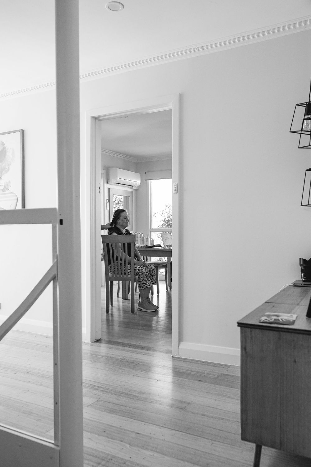 A minimalist interior hallway view through doorways with hardwood floors and white walls.