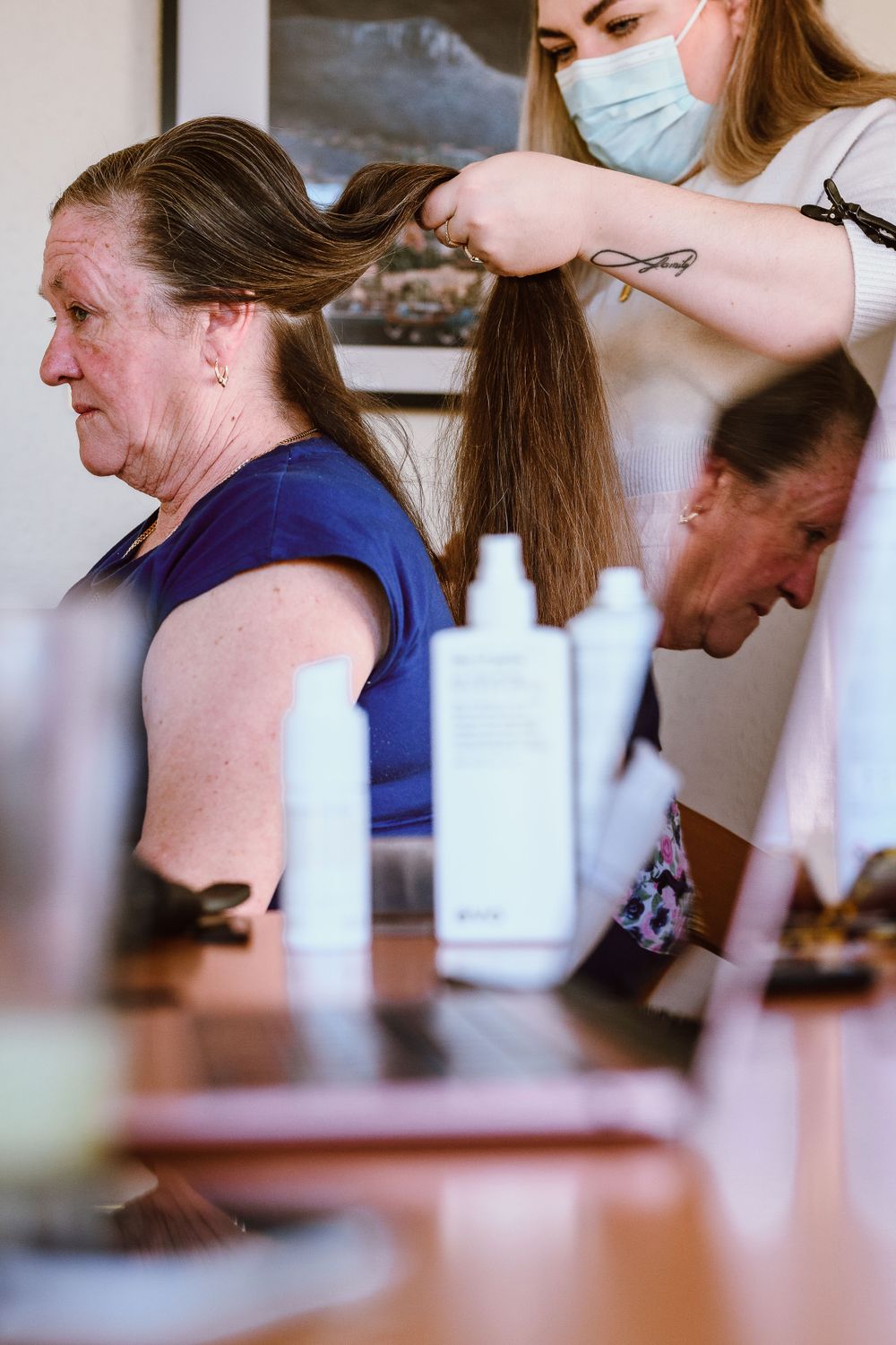A hairdressing session in progress with someone wearing a protective face mask and holding scissors.