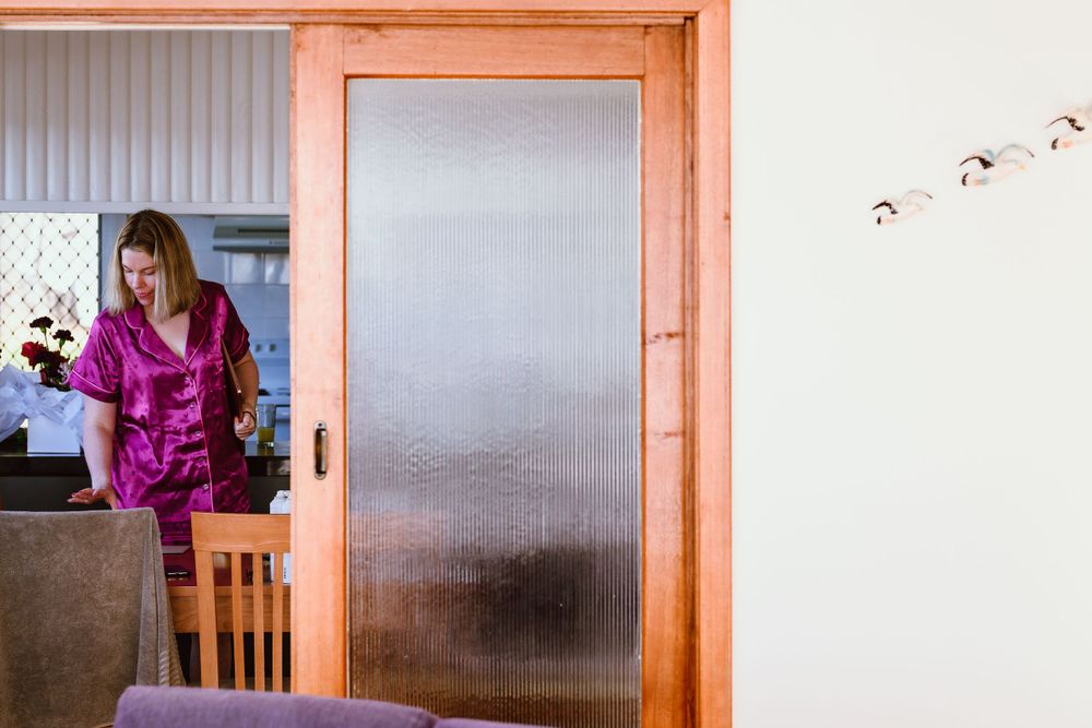 Someone in a bright pink shirt visible through a frosted sliding door frame.