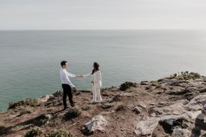 Buitenlands koppel houdt handen vast aan de rand van de Howth cliff walk in Ierland