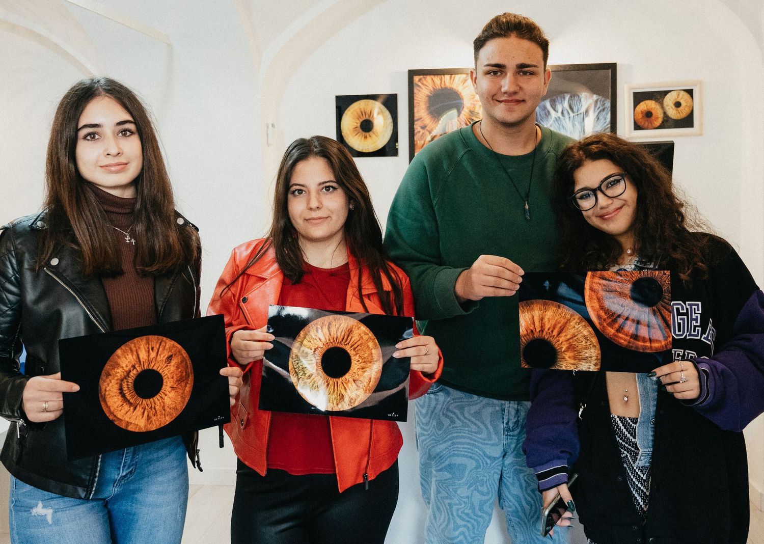 Group of people holding framed iris art photographs in a gallery setting.