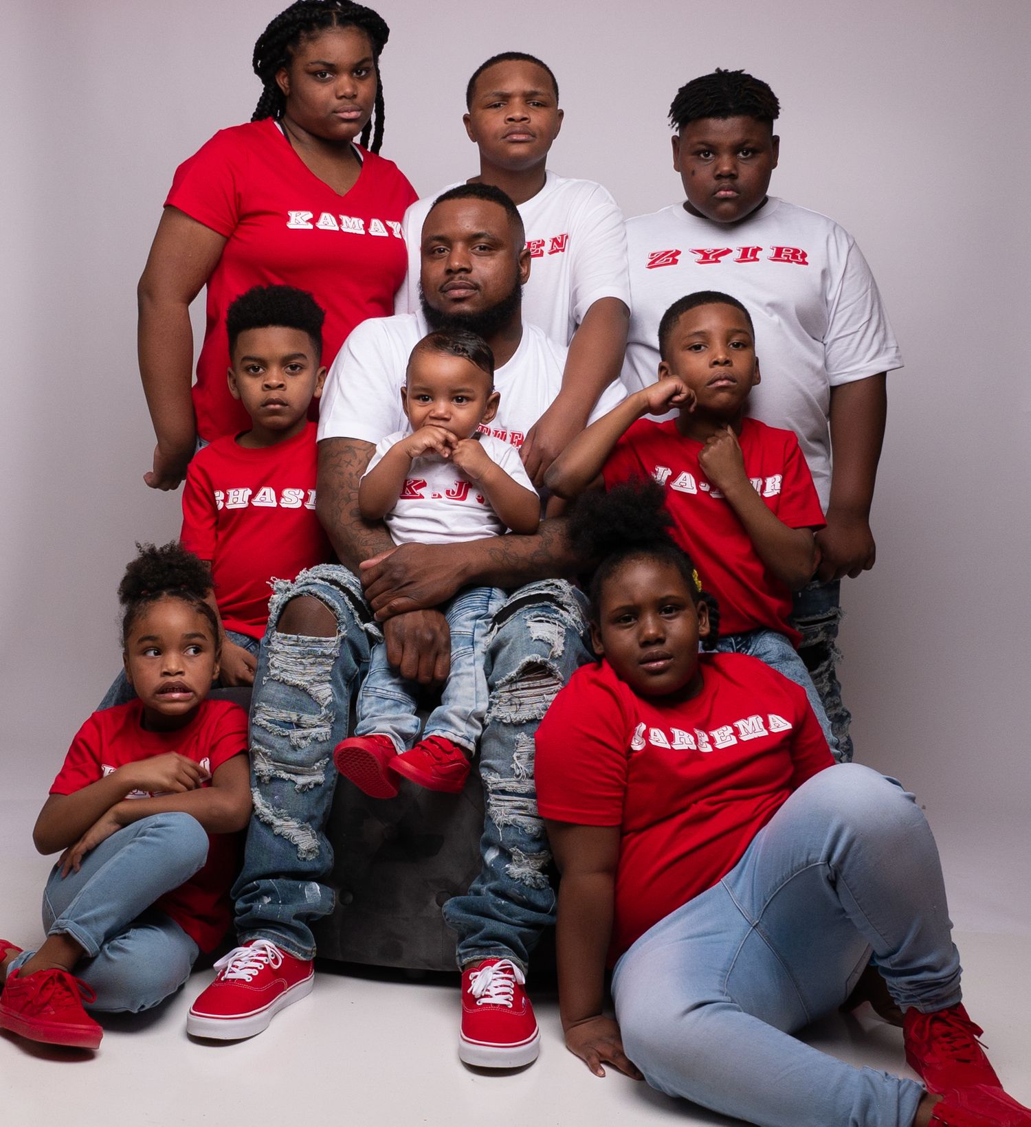 Family group in coordinated red and white shirts sitting for professional photography session.