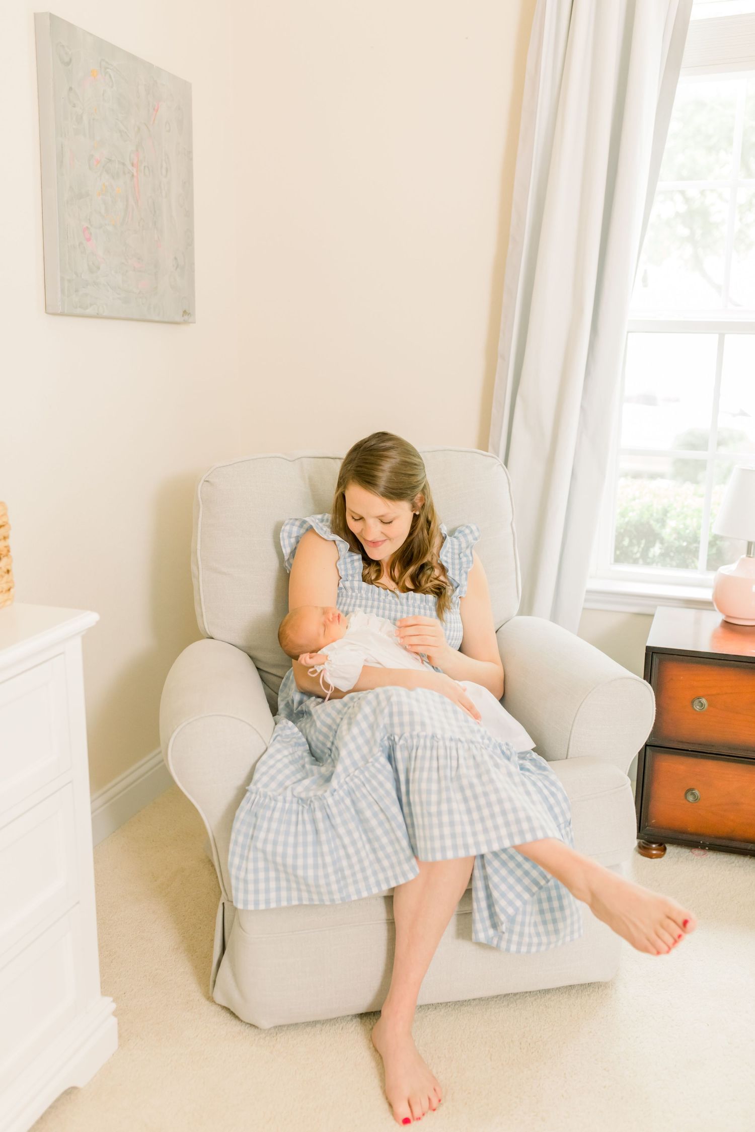 Person relaxing in comfortable gray armchair next to sunny window.