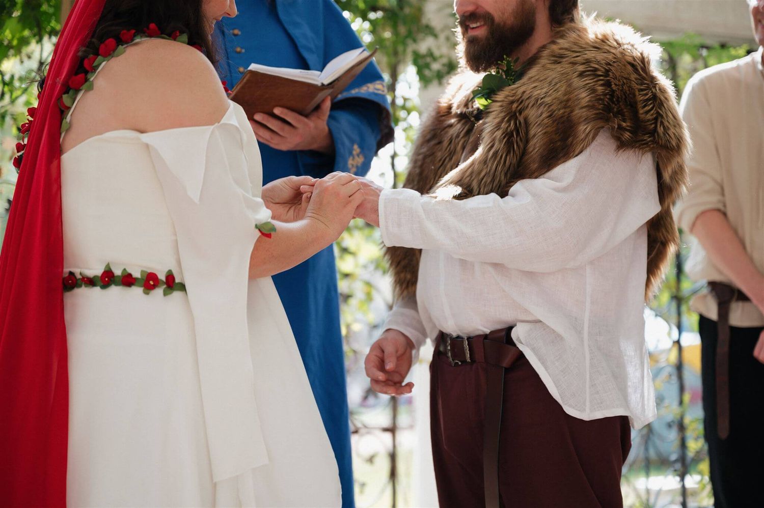 Close-up of a medieval-themed wedding ceremony showing hands clasping during an outdoor ceremony.
