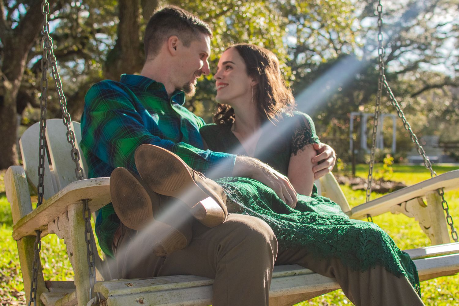 Couple relaxing together on wooden porch swing in sunlit garden.