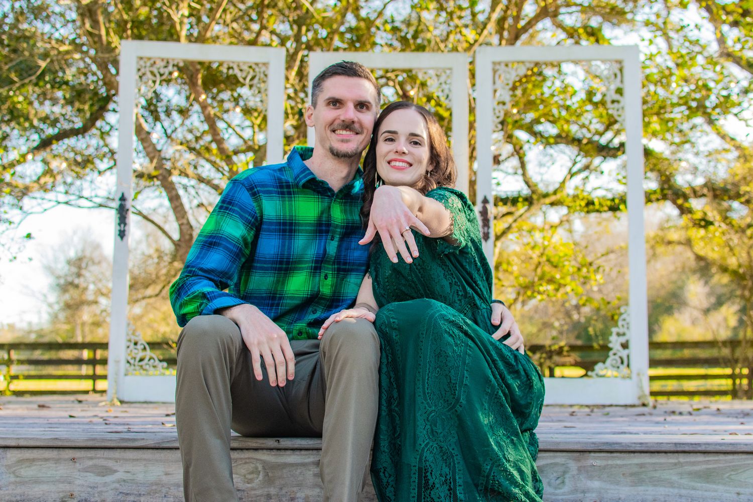 Couple in coordinated green outfits sitting together on white gazebo steps.