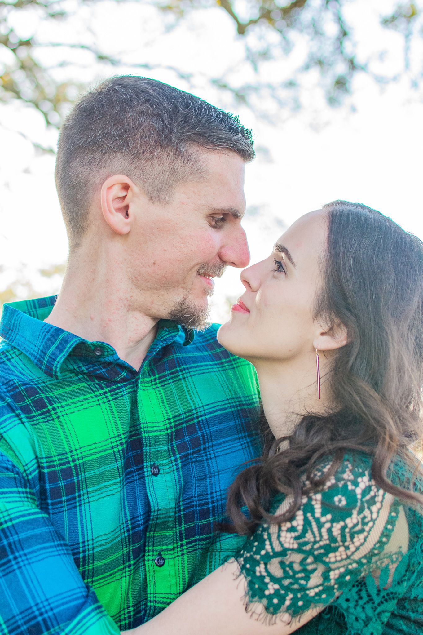 A romantic couple in coordinating green outfits share an intimate moment outdoors.