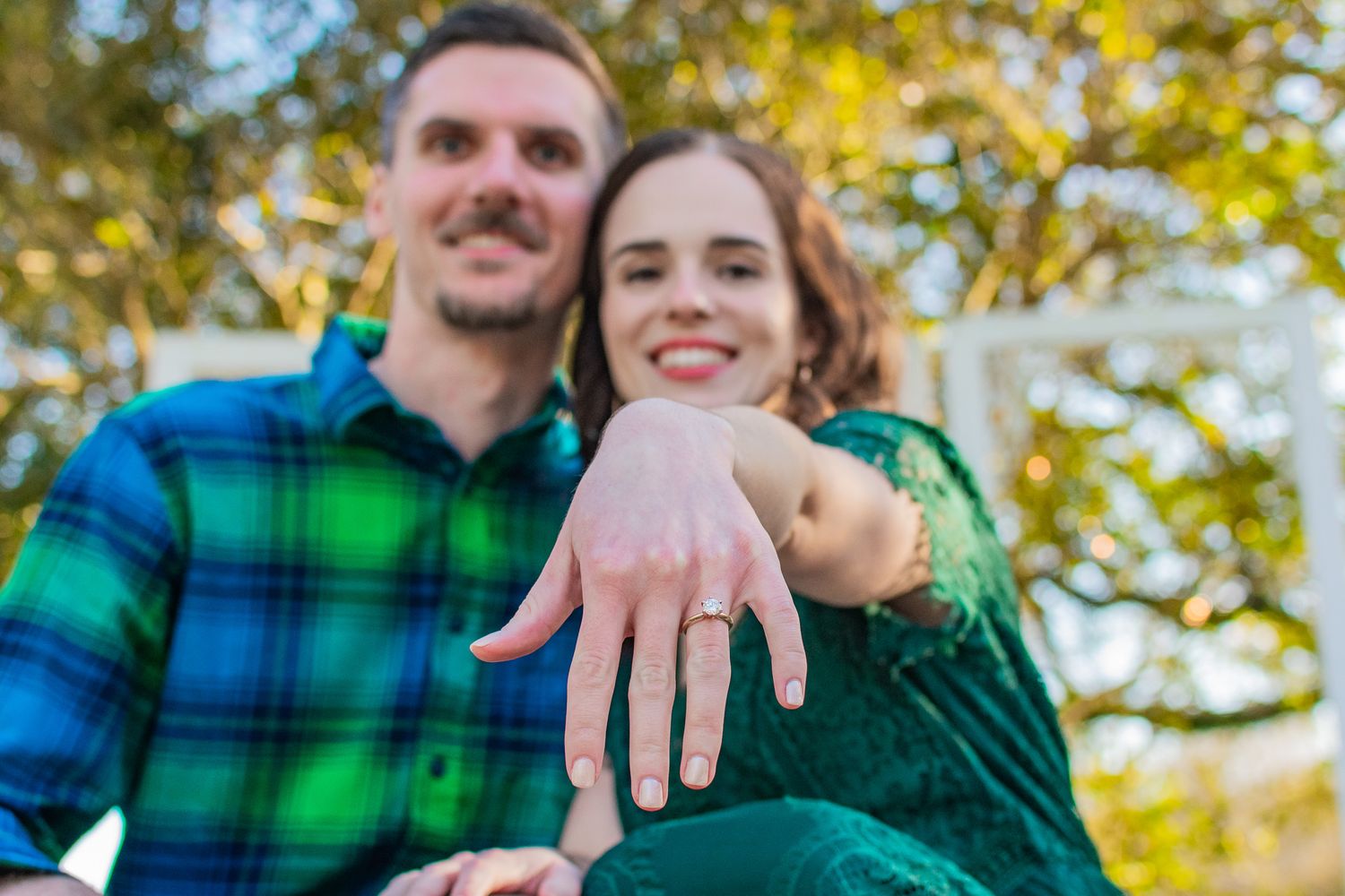 Engagement announcement showing couple in green with ring display.