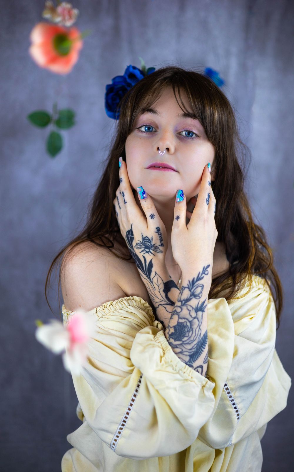 Fashion portrait in yellow off-shoulder top with visible tattoos and dramatic lighting.