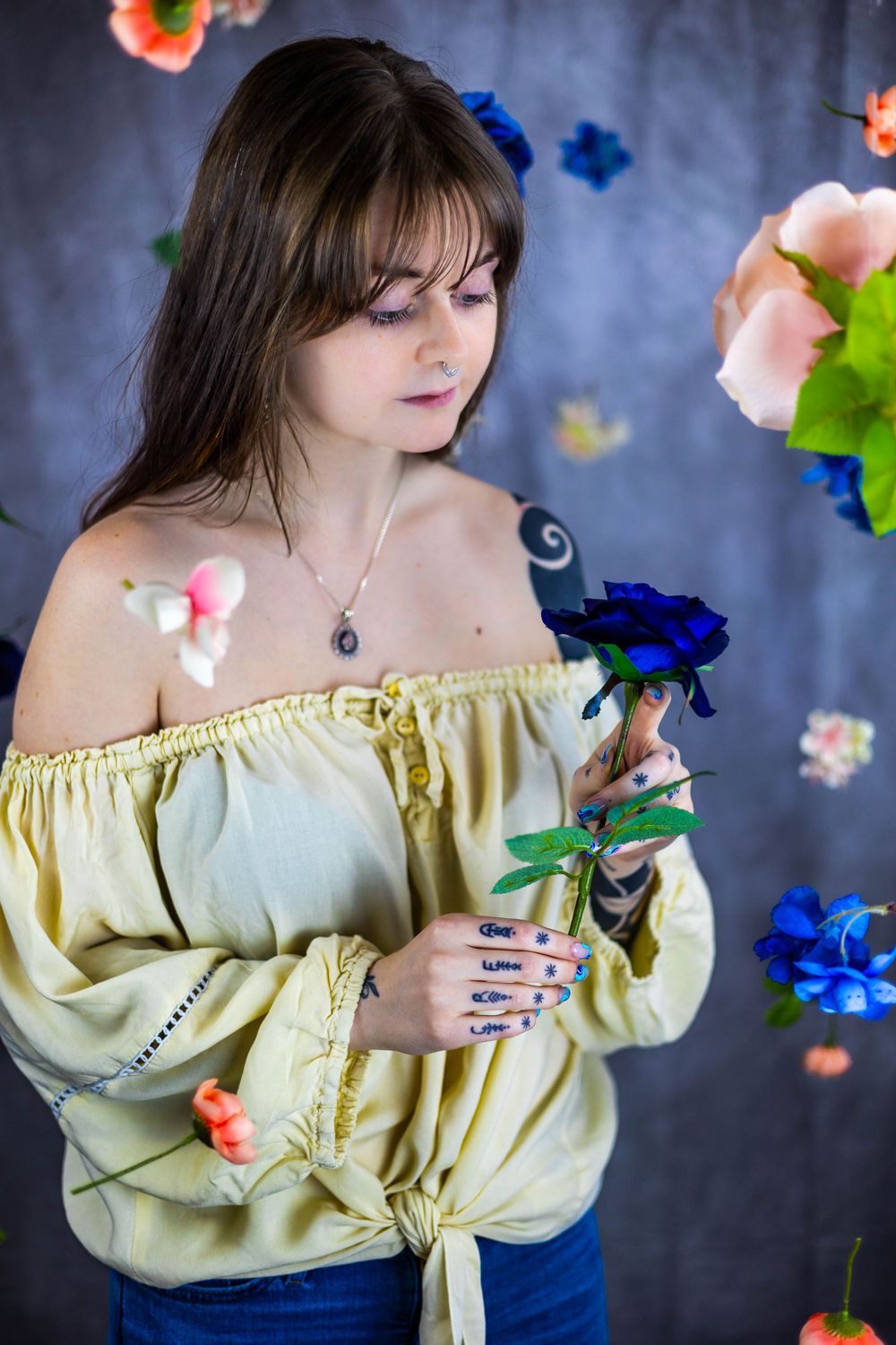 Ethereal fashion shoot with floating flowers and yellow off-shoulder blouse.