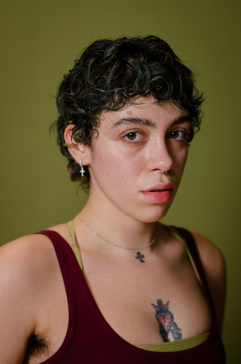 Close up headshot of an actor in a vest top against a green backdrop.