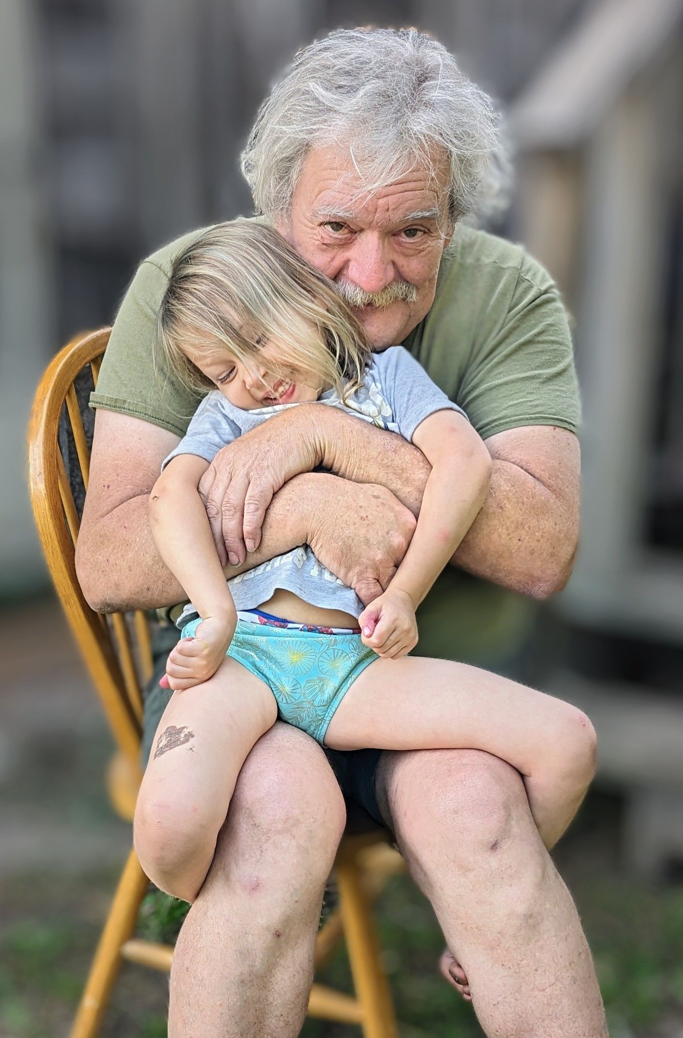 Sweet candid moment on wooden chair outdoors.
