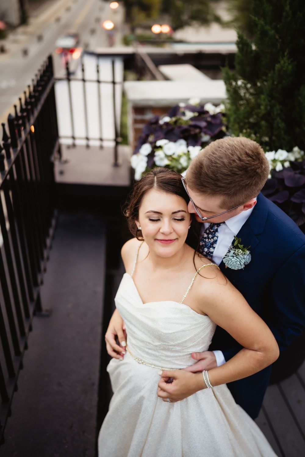 Romantic wedding portrait on an outdoor terrace with city views and floral decorations.