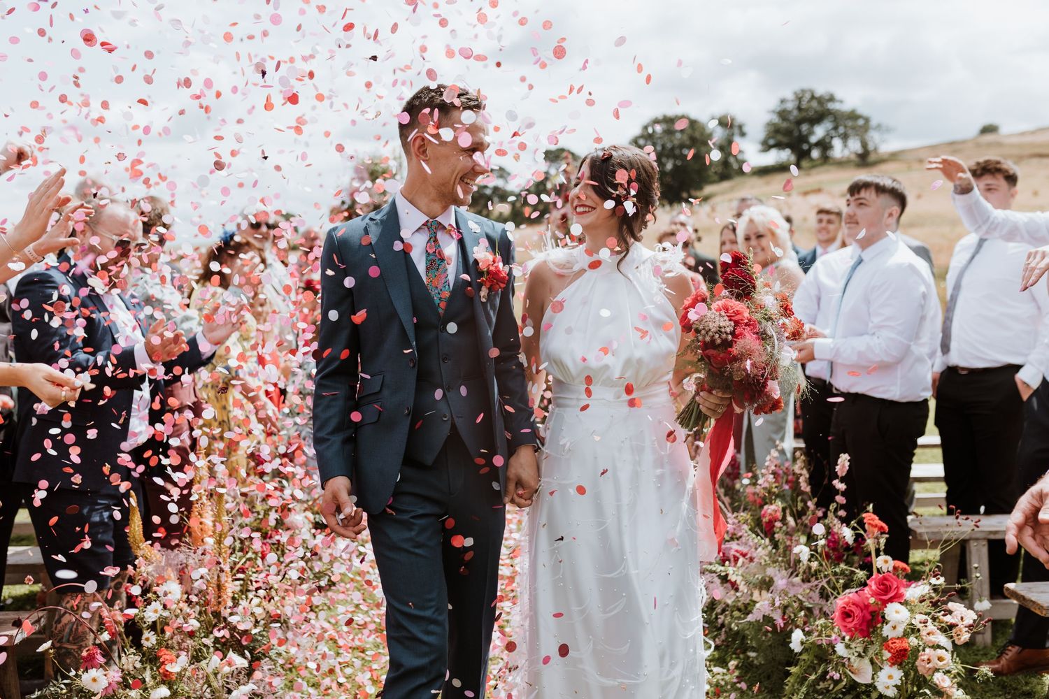 Wedding celebration with pink confetti being thrown during an outdoor ceremony among gorgeous floral decorations at Lyde Court