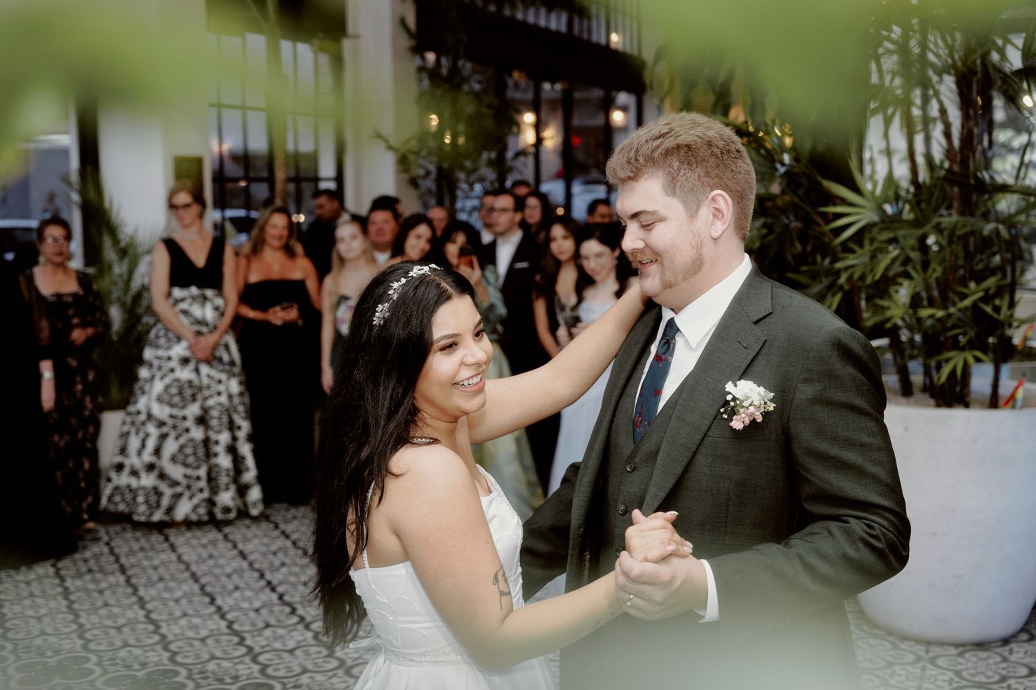 A couple shares their first dance at their wedding reception surrounded by guests.