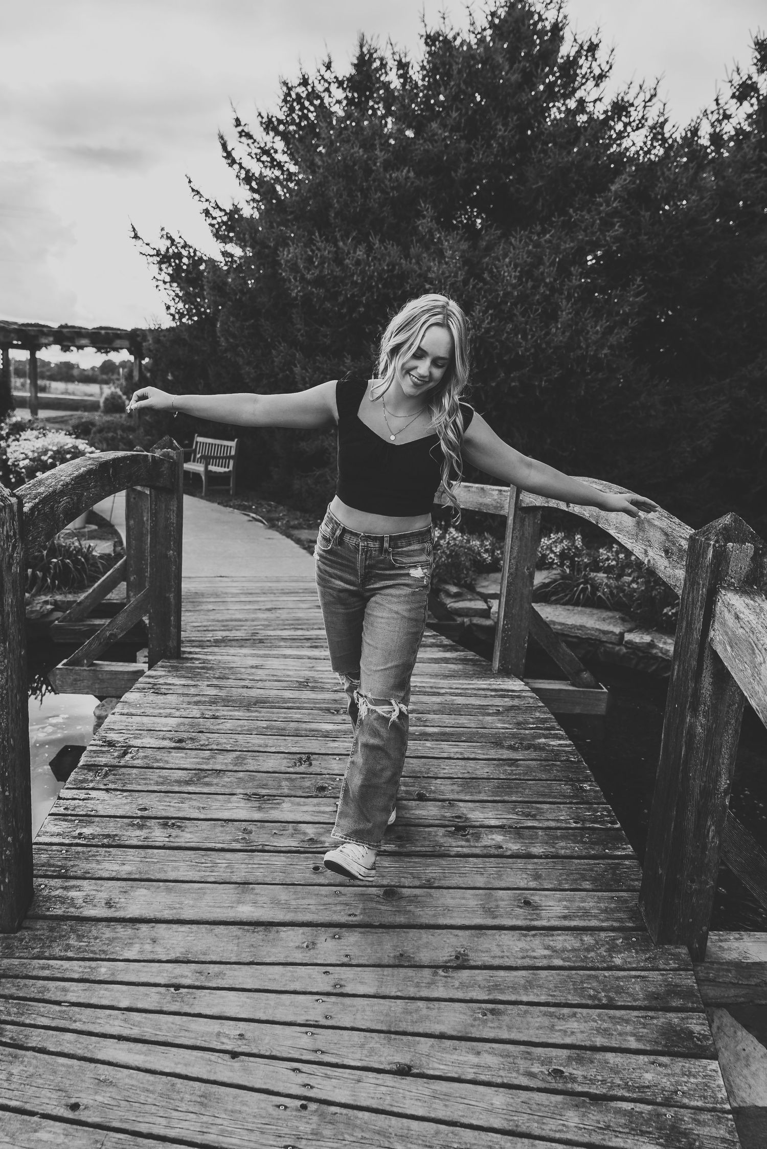 Person balancing playfully on wooden boardwalk in black and white photography.