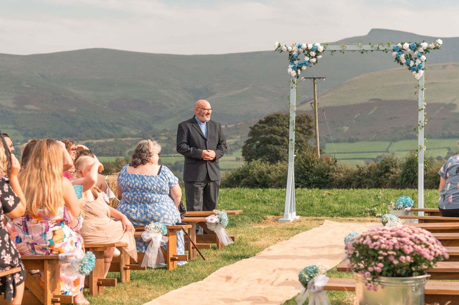 Outdoor wedding venue setup with mountains and green fields in the background.