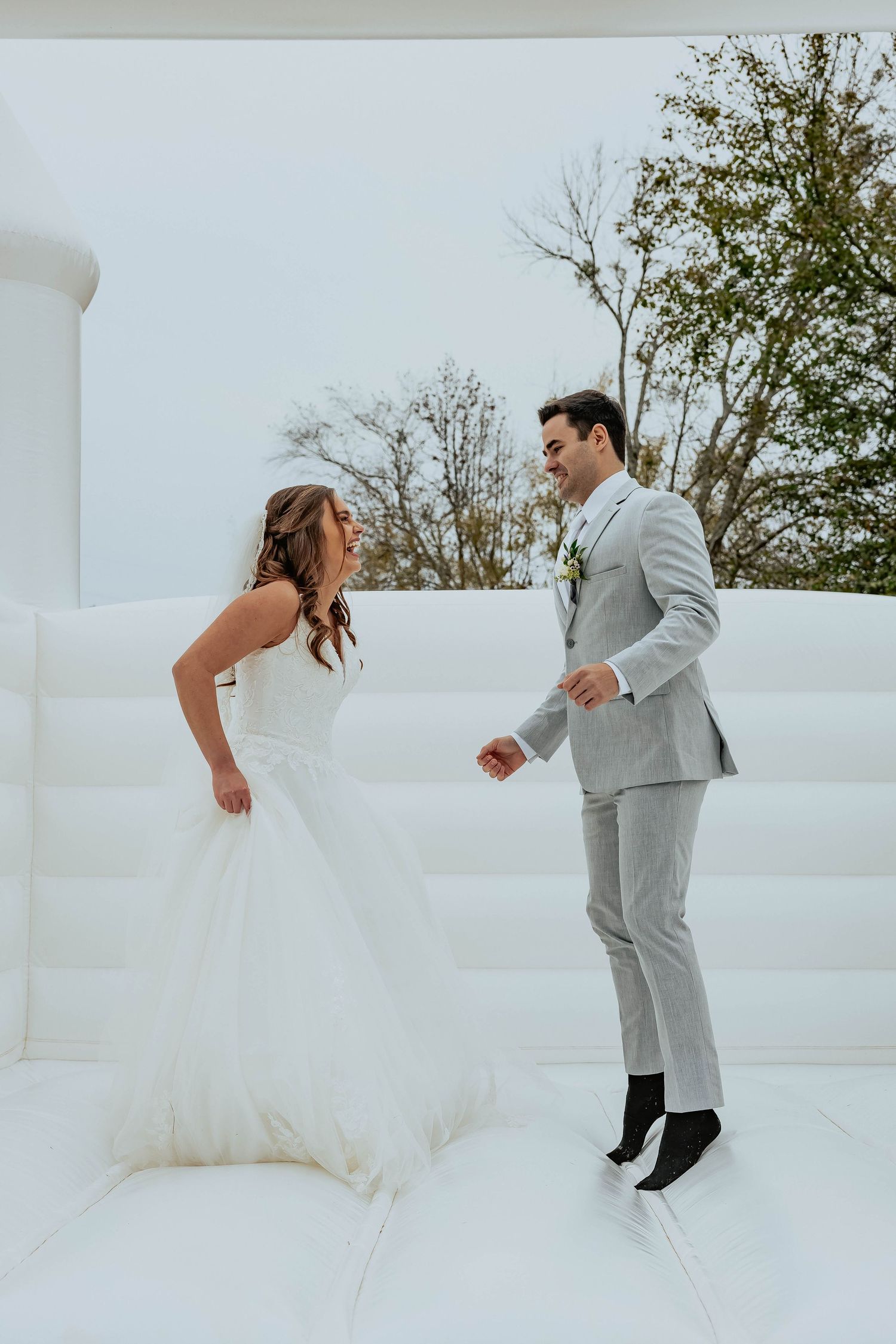 A playful wedding scene on an all-white bouncy castle or inflatable platform.