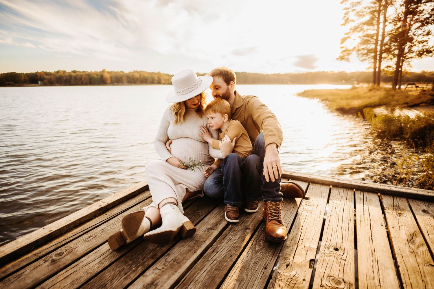 A cozy family moment shared on a wooden dock at sunset by the lake.