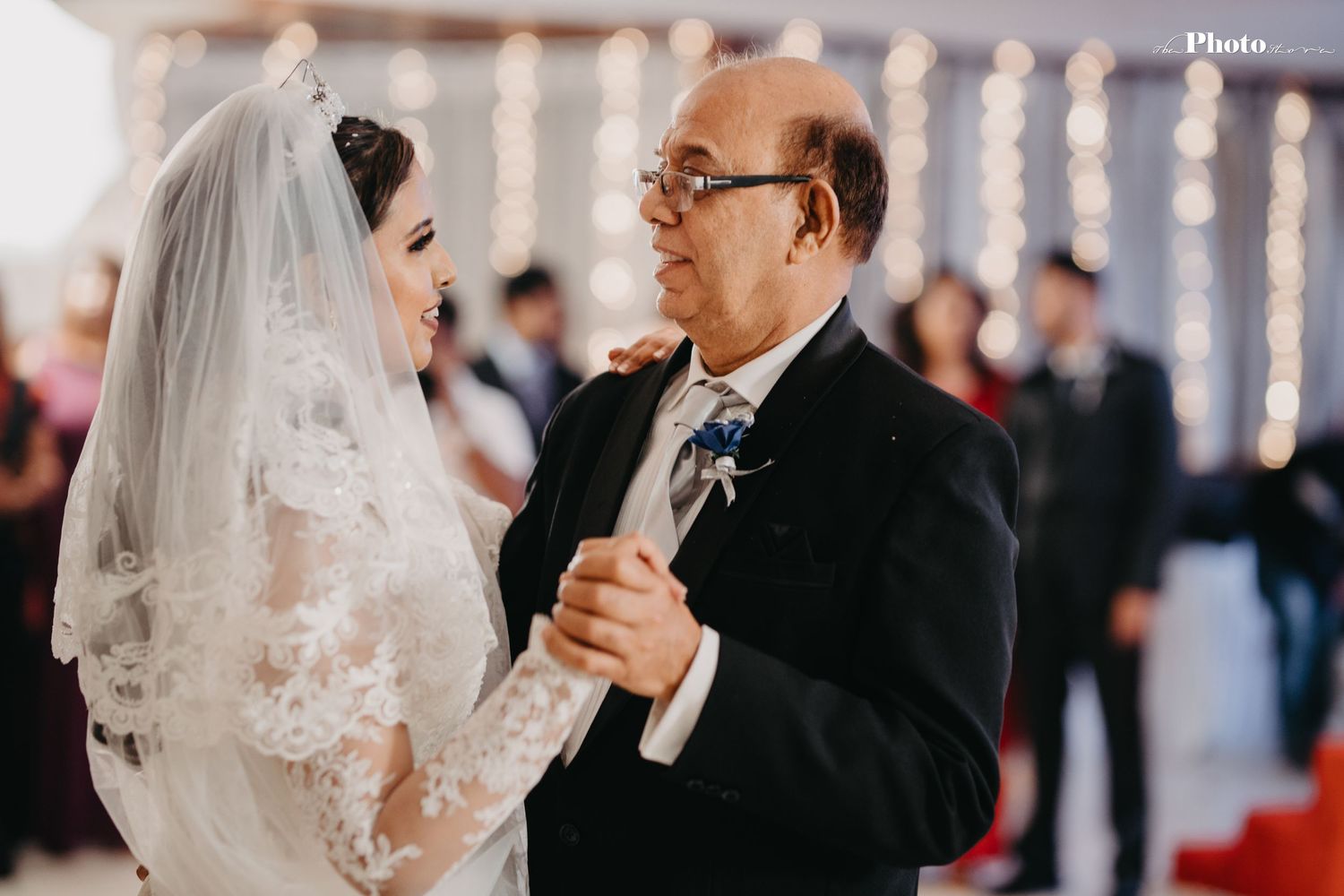 Romantic dance sequence captured under twinkling string lights at indoor wedding reception.