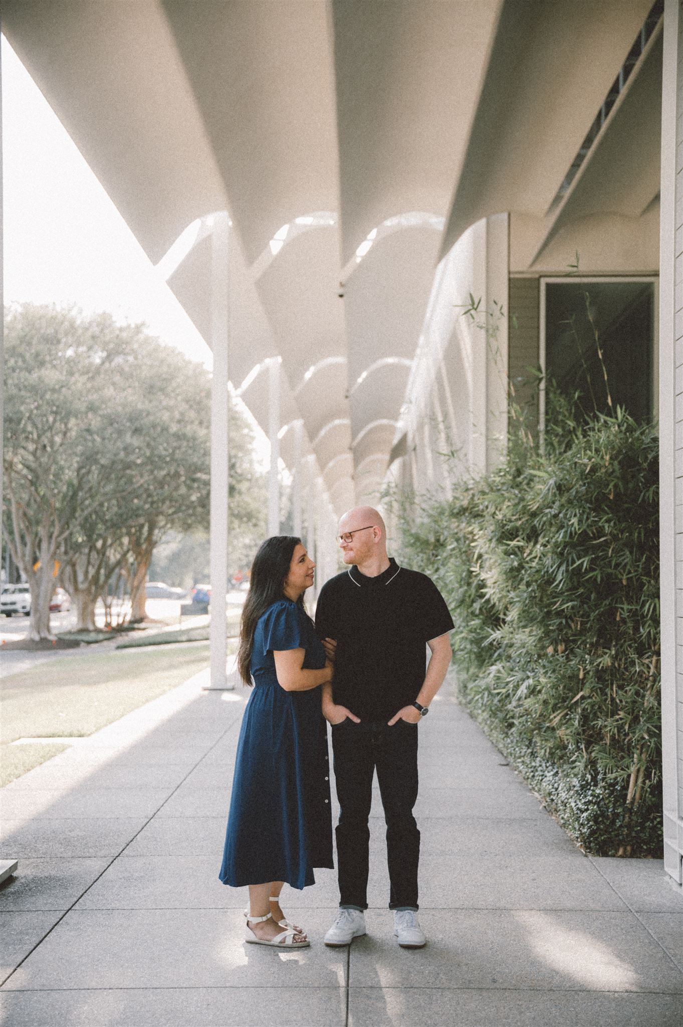 Two people share a moment under architectural beams casting dramatic rays of light.