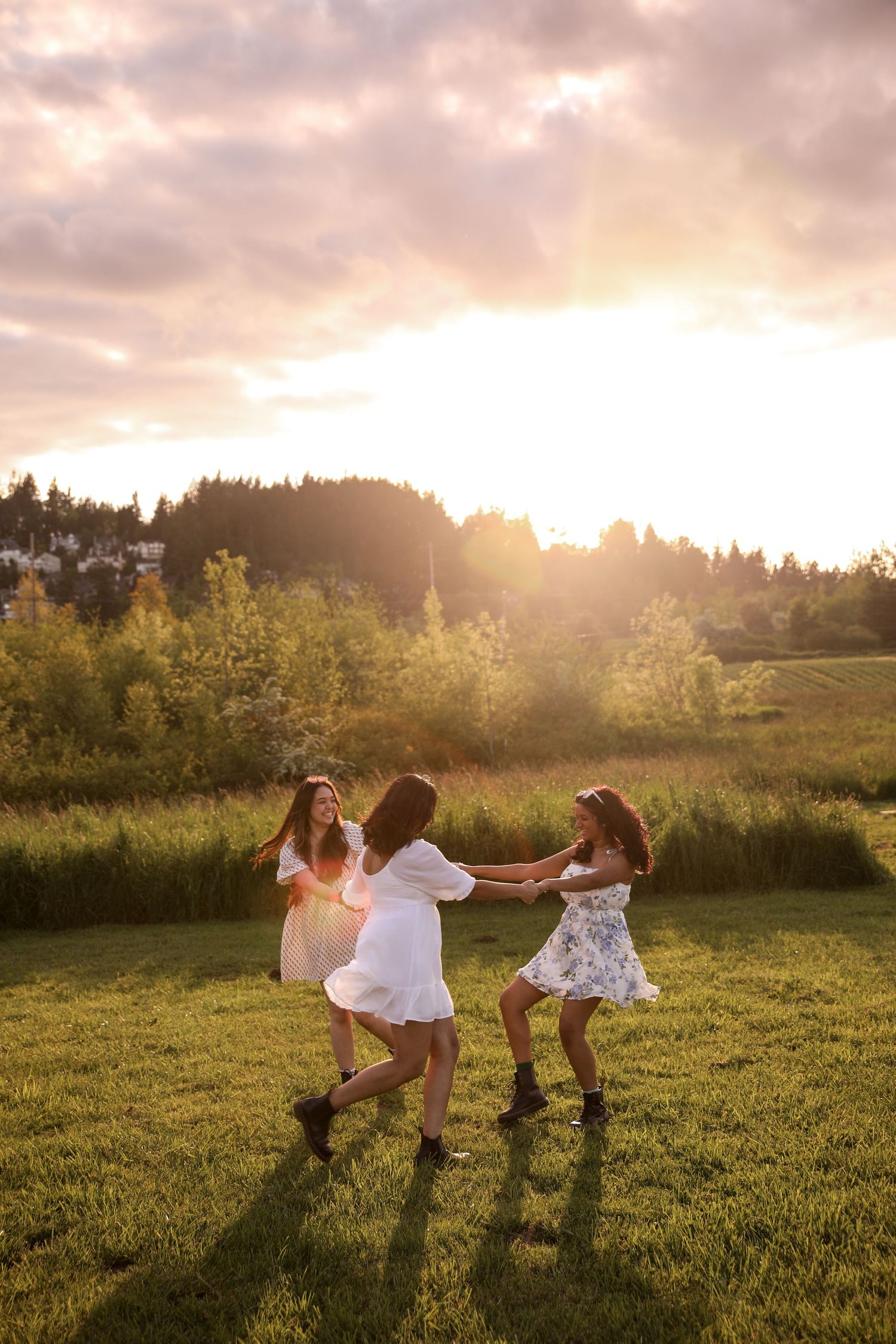 Three people dancing in a golden field at sunset with trees in the background.