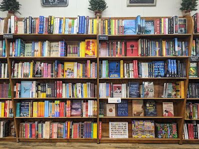 Colorful bookshelf filled with various books arranged neatly on wooden shelves.