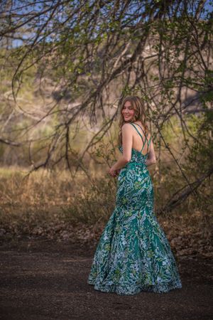 Full-length shot of teal mermaid dress with intricate pattern against natural backdrop.