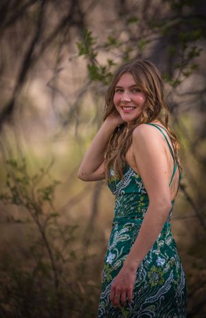 Portrait in natural lighting showing teal patterned dress with strappy back detail.