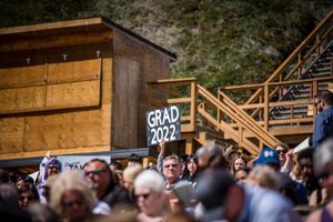 A graduation ceremony crowd with 'GRAD 2022' sign visible in an outdoor amphitheater.