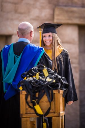 Graduate in cap and gown stands with faculty member during commencement ceremony.