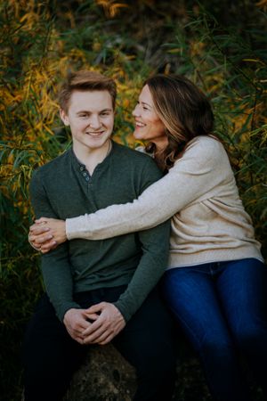 Joyful outdoor portrait featuring warm embrace against backdrop of golden autumn leaves.