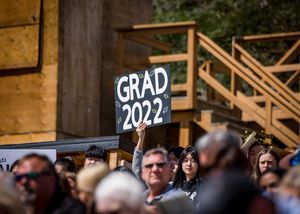 A 'GRAD 2022' sign visible above a crowd at graduation ceremony.
