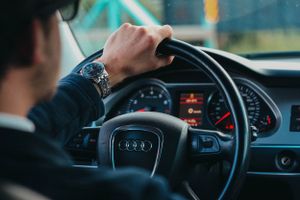 Close-up of hand on Audi steering wheel showing dashboard display.