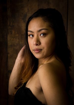 Elegant portrait featuring warm lighting and dramatic shadows against textured background.