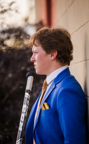A profile view of someone wearing a bright blue suit with gold tie and pocket square.