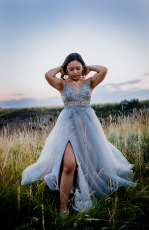 Ethereal pale blue gown with crystal details captured in natural meadow setting.