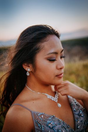 Close-up portrait showing sparkling jewelry and detailed beadwork on pale blue evening gown.