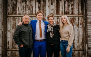 Family group poses together against weathered wooden barn door background.