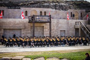 Wide shot of graduation ceremony with rows of graduates in black gowns at Drumheller Valley.