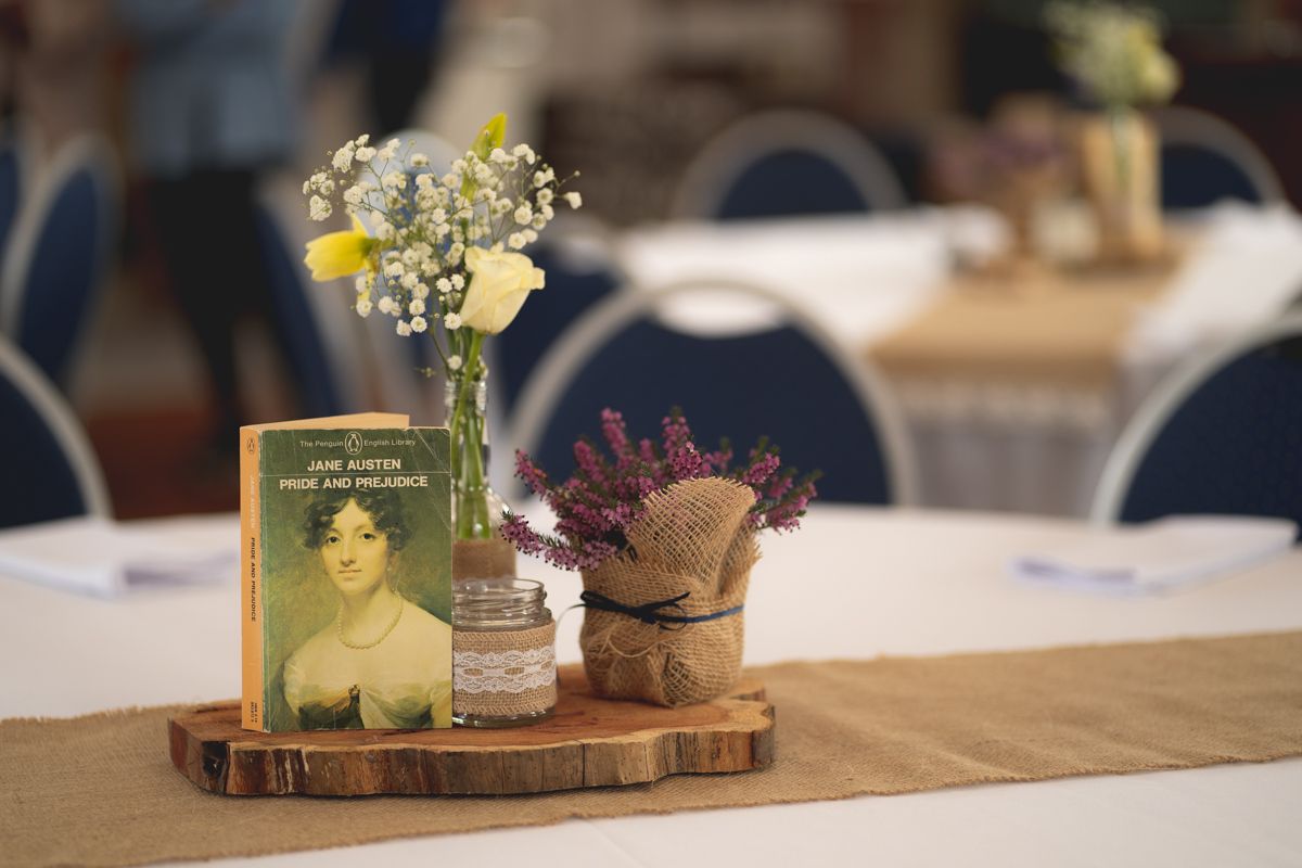 Rustic wedding centerpiece with vintage photo frame and wildflowers on wooden slice.