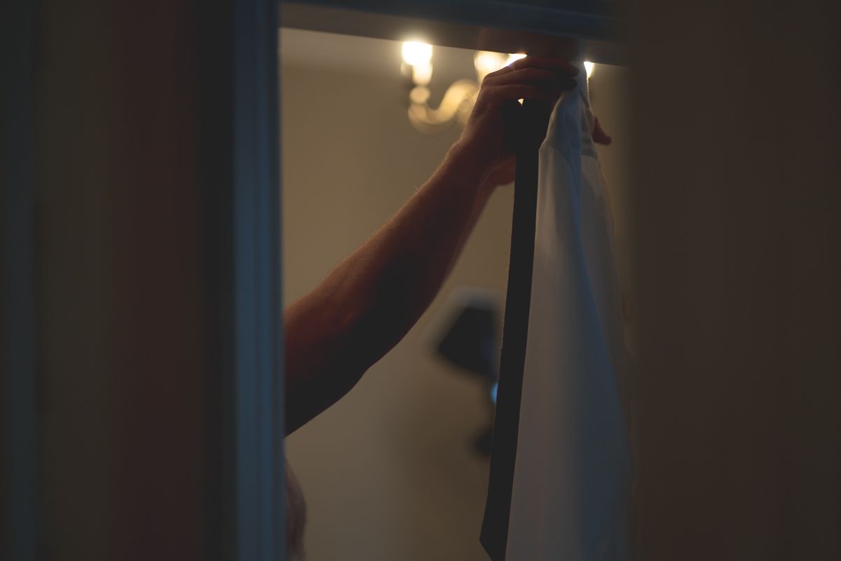 Silhouette of person adjusting something in a dimly lit room with light fixture visible.